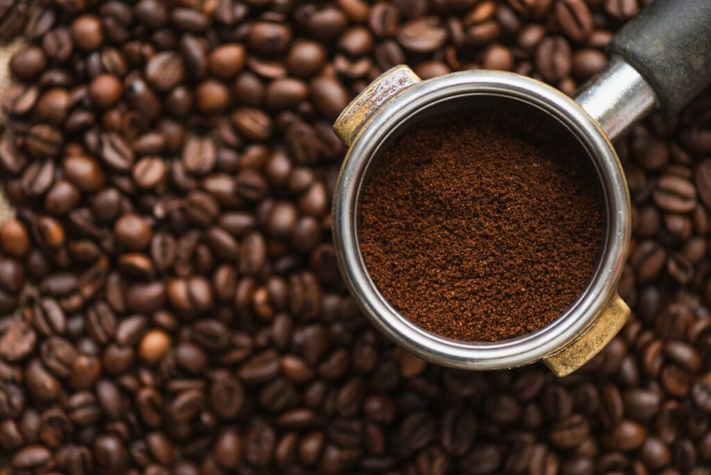 top view of ground coffee in portafilter on coffee beans background